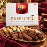Merci gift box with an assortment of wrapped chocolates on a gold tray
