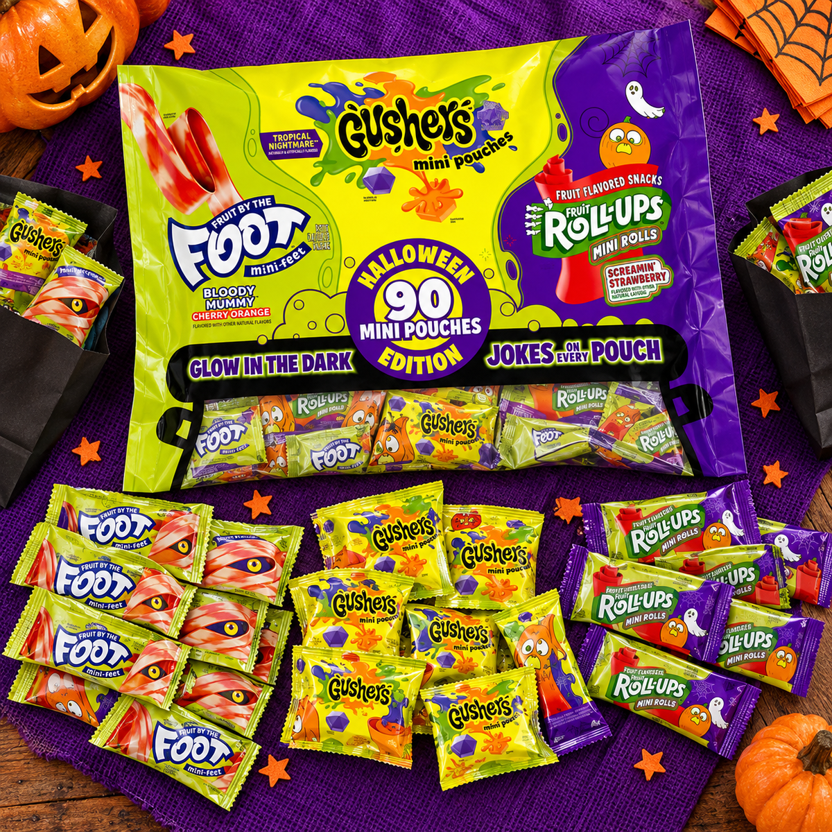 Halloween mini pouches of Fruit by the Foot, Gushers and Fruit Roll-Ups on a purple table