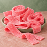 Strawberry Sour Belts in a bowl, chewy red sour candy strips coated in sour sugar