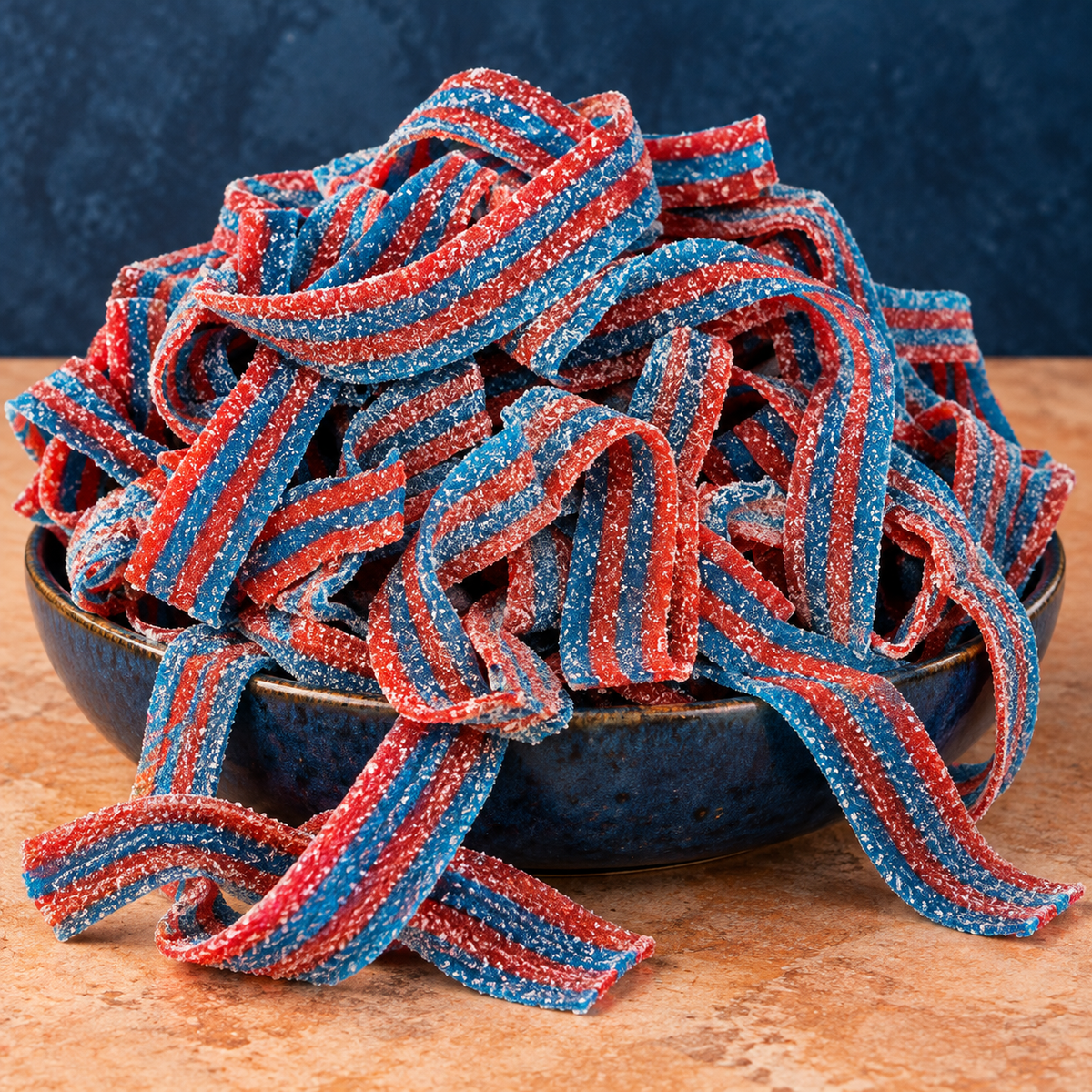 Blazpberry Sour Belts in a bowl, chewy red-and-blue striped sour candy strips coated in sour sugar
