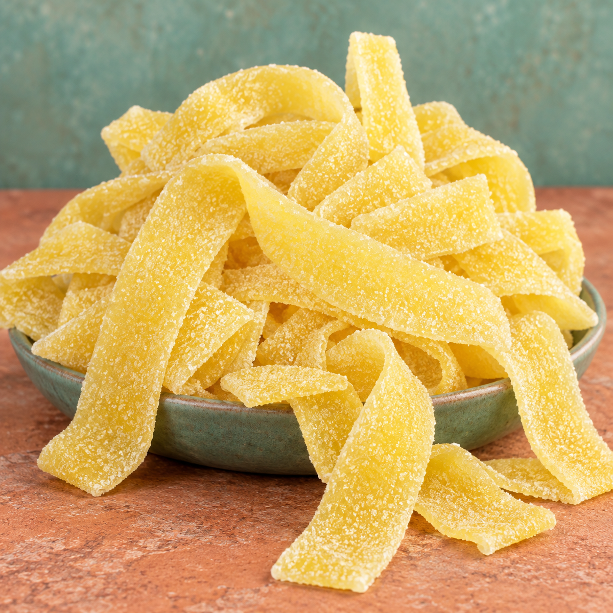 Mango Sour Belts in a bowl, chewy golden orange sour candy strips coated in sour sugar