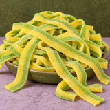 Pickle Sour Belts in a bowl, chewy green and yellow sour candy strips coated in sour sugar